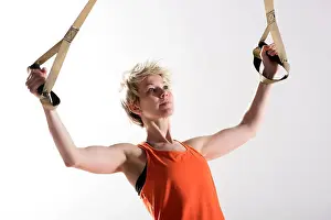 Pulling Prints: Single strong blond woman in orange sleeveless shirt pulling fitness cords