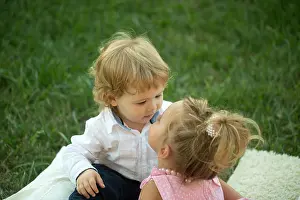 Sister Prints: Sister kiss brother with blond hair on green grass