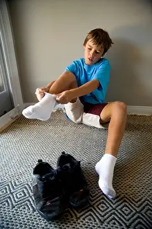 Floors Prints: Sitting on the floor by the front door a 10 year old boy dons his socks at home in Laguna Niguel CA