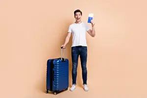 Tickets Prints: Full size photo of impressed brunet man stand hold tickets bag wear t-shirt jeans sneakers isolated on beige background