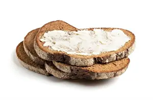 Baker Prints: A slice of black rye bread spread with butter on a white background