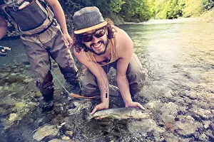 Catching Prints: Slovenia, two men fly fishing in Soca river catching a fish