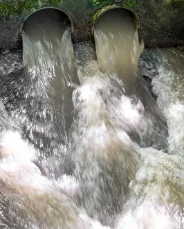 Drainage Prints: Slow motion shot of water sewage flowing through 2 pipe openings
