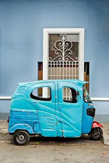 Urban Living Prints: A small blue delivery van is parked in front of a blue building on a side street in the Barranco neighborhood of Lima