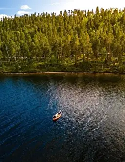 Outdoor Recreation Prints: A small boat drifts peacefully on the surface of a tranquil lake