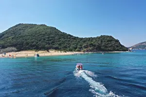 Agios Prints: Small boat with tourists heading to iconic small uninhabited island of Marathonisi featuring clear water sandy shore