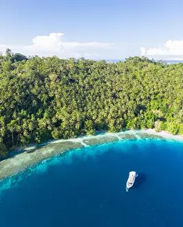 A small dive boat is anchored off the coast of Papua New Guinea. This tropical area is part of the Coral Triangle due to its high marine biodiversity