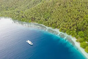 A small dive boat is anchored off the coast of Papua New Guinea. This tropical area is part of the Coral Triangle due to its high marine biodiversity
