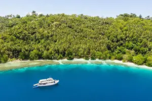 A small dive boat is anchored off the coast of Papua New Guinea. This tropical area is part of the Coral Triangle due to its high marine biodiversity