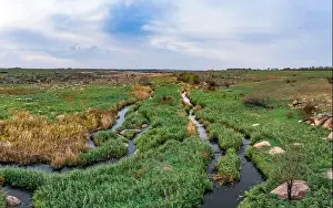 A small fast stream Kamenka in the wilderness in the evening light in Ukraine. Aerial panoramic drone shot