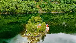 Building House Prints: small, green island with two red cabins nestled amongst trees in a secluded Norwegian fjord