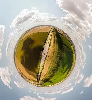 Small planet with a view of a bridge and wheatfields under the blue sky in Moldova