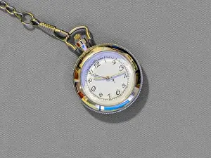 Timer Prints: Small steel pocket watch with white dial, metal object on gray uniform background