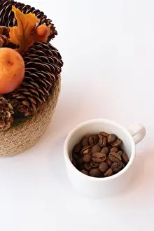 High Key Prints: Small white cup of coffee beans next to a fall decoration made of pine cones