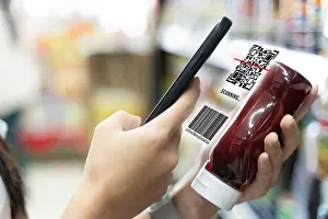 Reader Prints: Smartphone scanning a product's QR code and barcode in a supermarket aisle