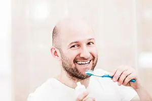 Dental Prints: Smiling bald man holding toothbrush with toothpaste and brushing teeth
