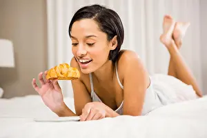 Pajamas Prints: Smiling brunette eating croissant