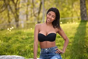 Green Park Prints: Smiling Colombian woman standing in black crop top and jeans under warm sunlight in a Toronto park