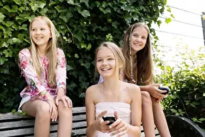 Female Friends Prints: Three smiling girls sitting on a park bench
