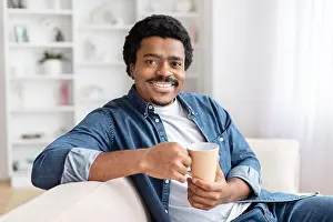 Empty Space Prints: Smiling man holding a coffee mug comfortably