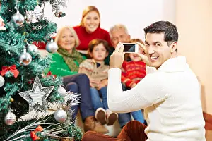 Citizens Prints: Smiling man taking family picture at christmas with his smartphone camera