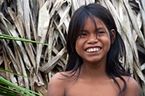 A smiling Matses Mayorunas young girl in front of a maloca (traditional house), Amazonian Peru