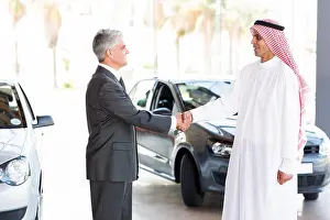 Business Man Prints: smiling middle aged car dealer handshake with Arabian man