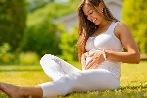 Abdomen Prints: Smiling pregnant woman forming a heart on the belly with her hands