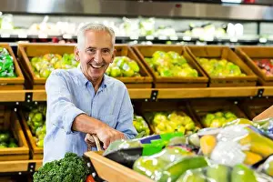 Single Person Prints: Smiling senior man browsing fresh produce in grocery store produce section