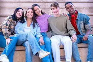 Having Fun Prints: Smiling Teenagers sitting on stairs hugging each other looking at camera