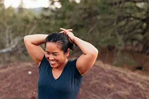Campsite Prints: Smiling Thai woman outdoors tying hair into ponytail while camping
