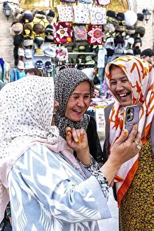 Uzbek Prints: Smiling women looking at a cell phone in Bukhara, Uzbekistan
