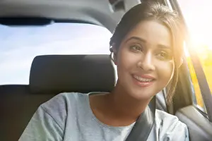 One Young Woman Only Prints: Smiling young woman wearing eyeglasses looking out of car window