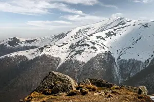 Snowy hills with orange grass and clear blue sky in spring mountains. Landscape photography