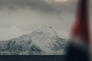 Brim Prints: Snowy mountain behind Norwegian flag in the arctic Lyngen Alps in Norway