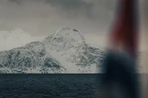 Brim Prints: Snowy mountain behind Norwegian flag in the arctic Lyngen Alps in winter