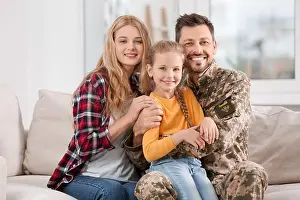 Preteen Prints: Soldier in Ukrainian military uniform reunited with his family on sofa at home