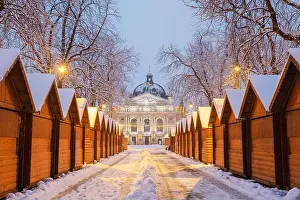 Solomiya Krushelnytska Lviv State Academic Theatre of Opera and Ballet in winter time. Wooden Christmas fair kiosk in a row with city light in