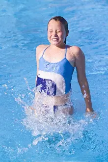 SPAIN IBIZA 10 YEAR OLD GIRL CHILD FEMALE LYING JUMPING OUT OF THE WATER FROM A SWIMMING POOL SMILING HAPPY FUN PLAY