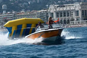 French Riviera Prints: A speed boat pulling a banana boat in the Mediterranean at Nice, Cote d'Azur, France