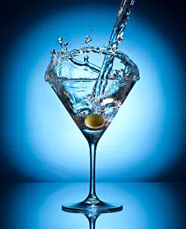 Bartender Prints: Splash martini from flying olives. Object on a blue background