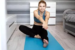 Shaping Prints: Sport, training and lifestyle concept - woman stretching leg on blue yoga mat at home in the living room