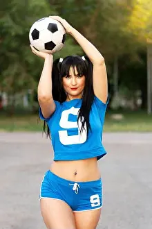 Kicker Prints: Sports girl in blue sports uniform posing with a ball as a football player against blurred background