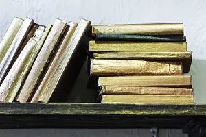 Bookshelf Prints: Stack of old books with golden covers on the shelf