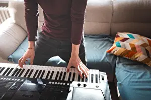 Piano Prints: Standing musician playing a digital keyboard in a brightly lit living room