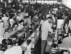 It is standing room only at a busy soda fountain lunch hour at a modern drugstore