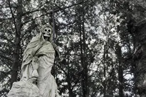 Ghost Prints: Statue of a skullfaced grim reaper made of stone with a tall scythe in his left hand