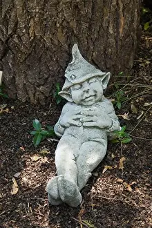 Sleepy Prints: Statuette of sleeping leprechaun next to tree trunk in backyard country garden in summer