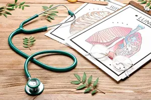 Stethoscope with drawings of human lungs and ribs on wooden background