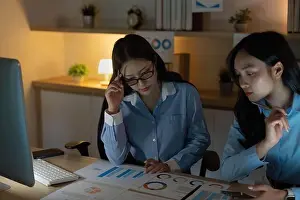 Commitment Prints: Strategic Planning. Two women analyzing budget data and charts in a cozy office environment